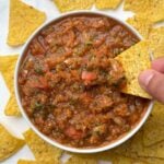 fresh homemade salsa served in a bowl and tortilla chips dipped inside the salsa