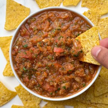 fresh homemade salsa served in a bowl and tortilla chips dipped inside the salsa