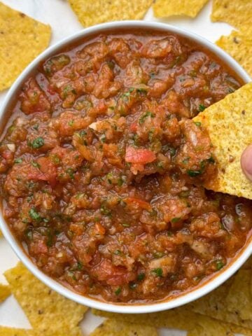 fresh homemade salsa served in a bowl and tortilla chips dipped inside the salsa