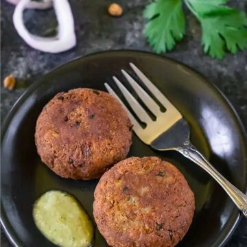 Kala chana kabab served on a plate with chutney on the side and fork on the plate.