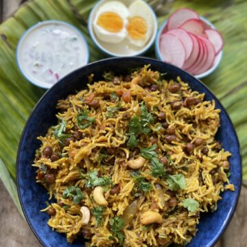 kala chana pulao in a bowl with raita and vegetables on the side