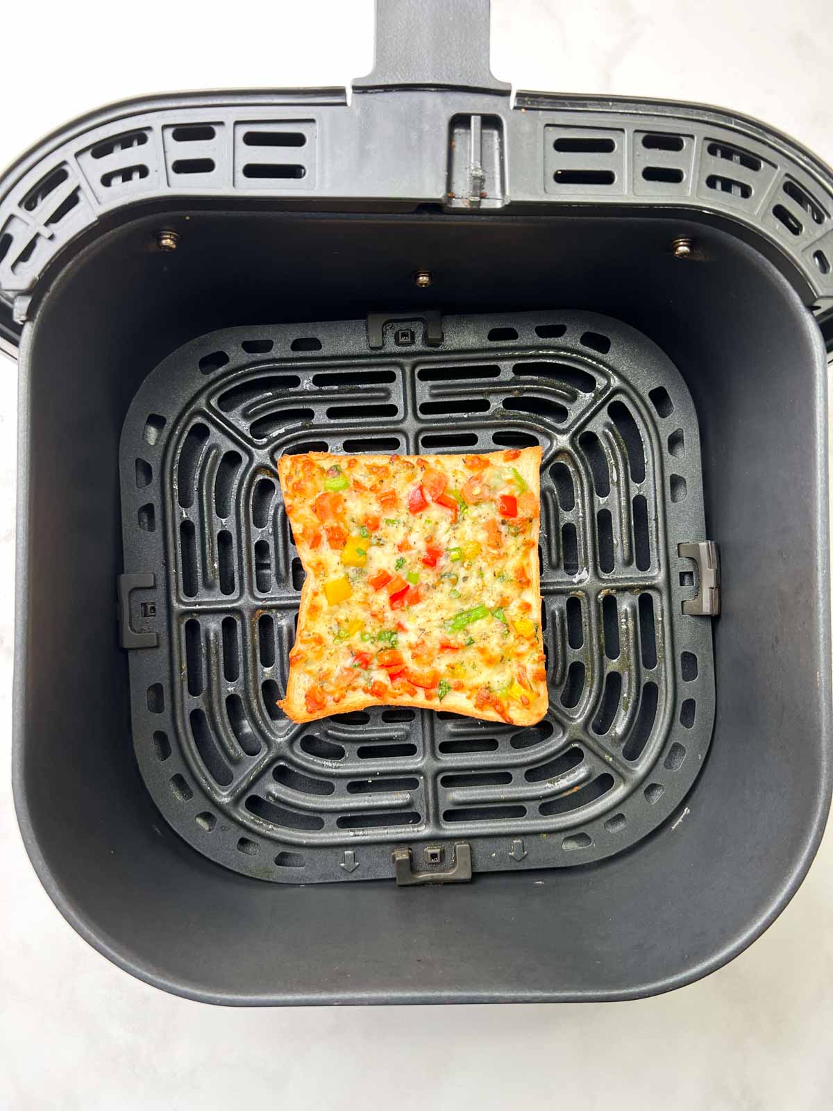 Perfectly air fried chili cheese toast in the air fryer basket.