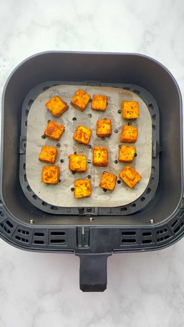 Crispy air-fried paneer pieces on the air fryer basket.