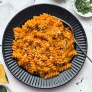 Creamy Gochujang Pasta served in a black plate with a spoon with parsley on the side.