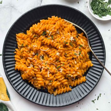 Creamy Gochujang Pasta served in a black plate with a spoon with parsley on the side.