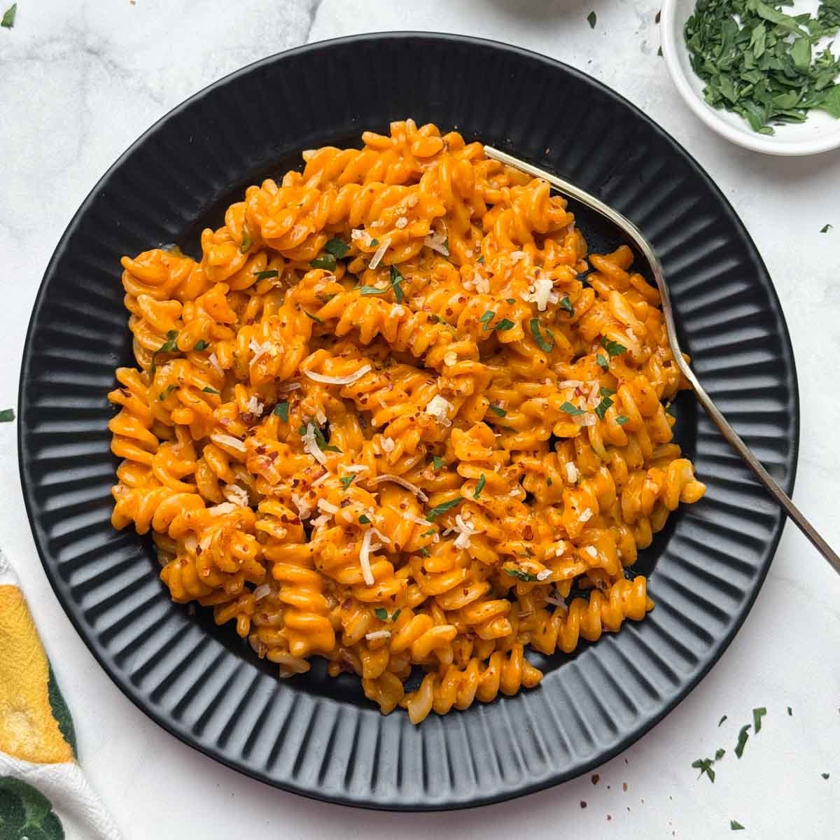 Creamy Gochujang Pasta served in a black plate with a spoon with parsley on the side.