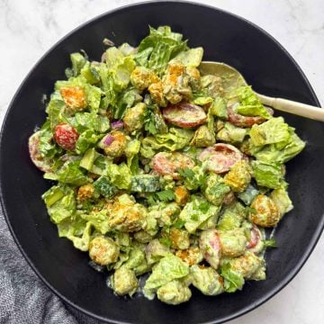 High protein soya chunks salad with greek yogurt dressing on a black bowl with a golden spoon on it.