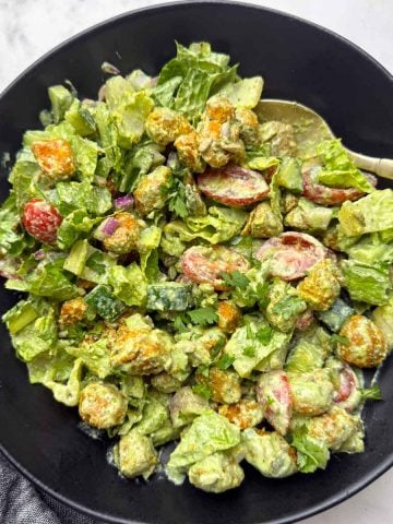 High protein soya chunks salad with greek yogurt dressing on a black bowl with a golden spoon on it.