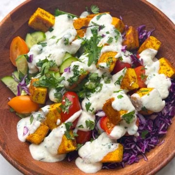 Indian style tofu salad with yogurt dressing in a wooden bowl.