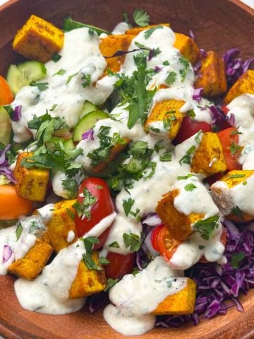 Indian style tofu salad with yogurt dressing in a wooden bowl.