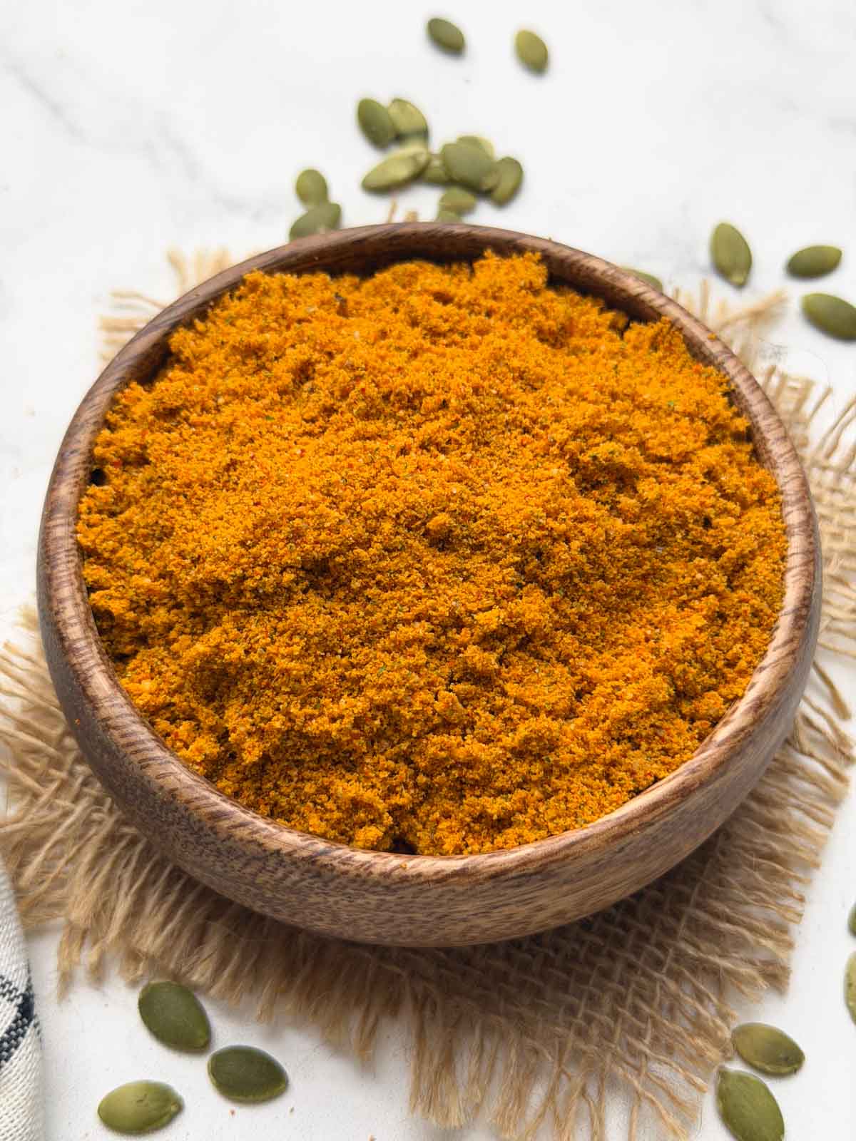 Pumpkin Seeds Chutney Powder served in a wooden bowl with pumpkin seeds on the surface for decoration.