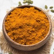 Pumpkin Seeds Chutney Powder served in a wooden bowl with pumpkin seeds on the surface for decoration.