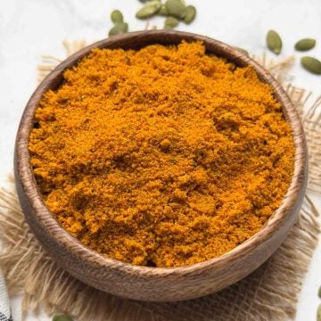 Pumpkin Seeds Chutney Powder served in a wooden bowl with pumpkin seeds on the surface for decoration.