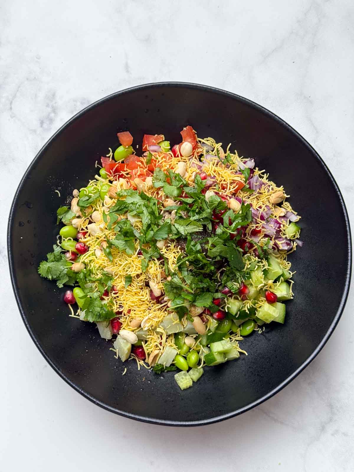 Step to add all the ingredients for the chaat in a black bowl