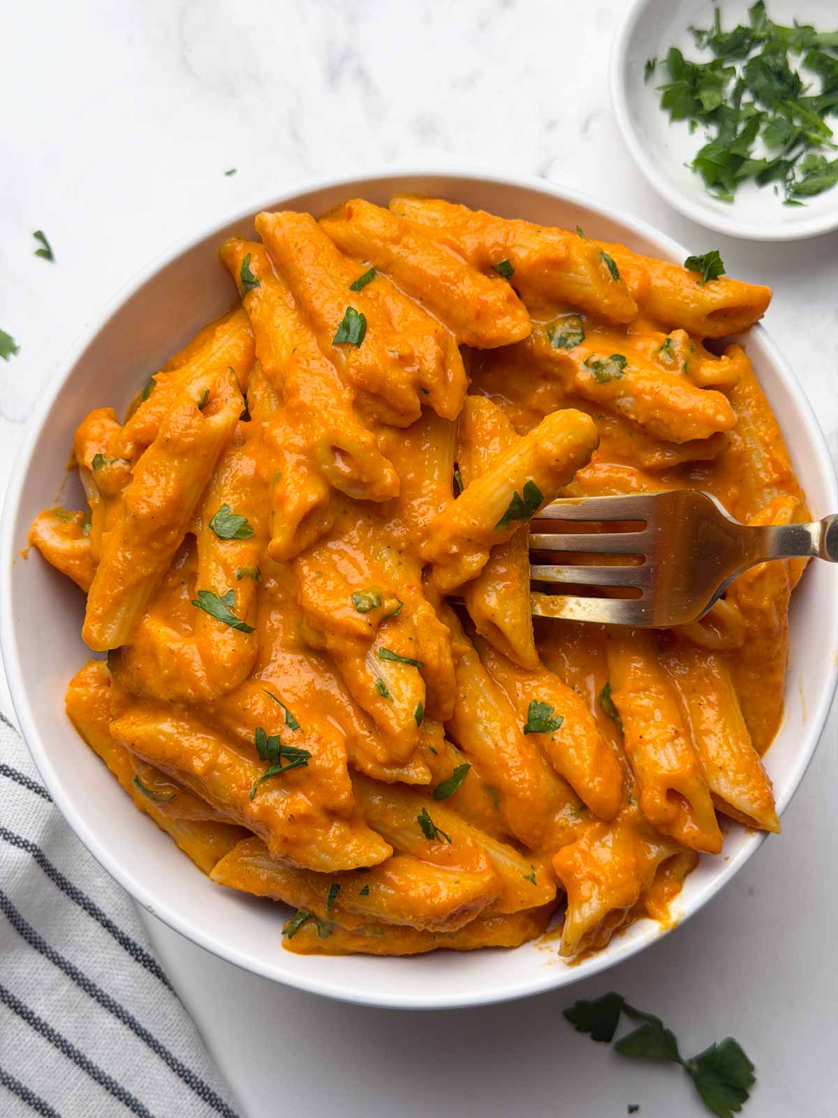 Hidden veggie pasta served in a white bowl with a fork digging into the creamy vegetable sauce.