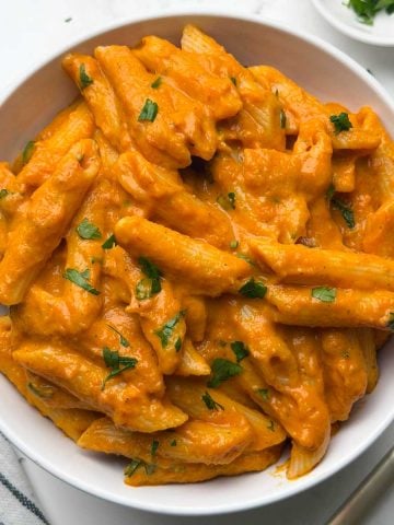 Bowl of hidden veggie pasta with golden fork and parlsey on the side.