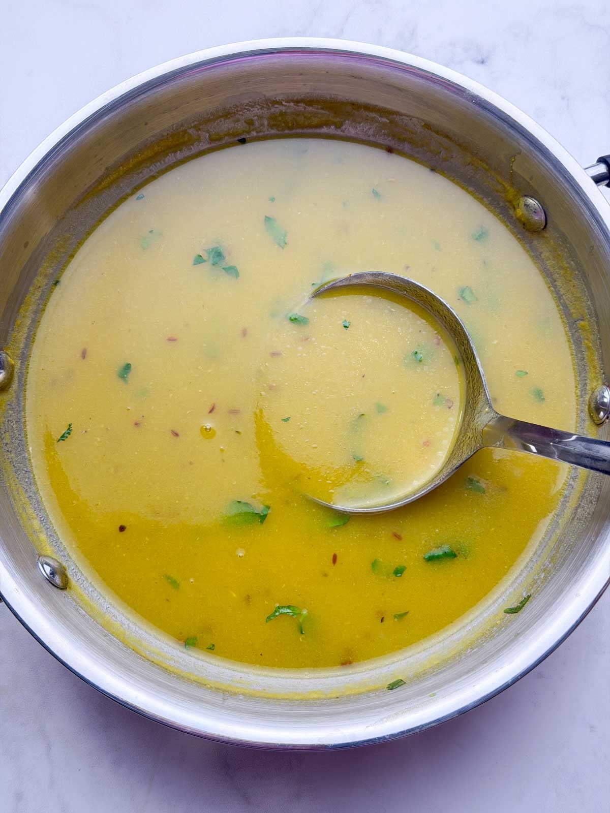 Drumstick soup in a kadai with spoonful of soup