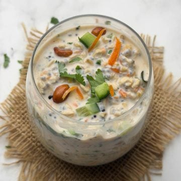 Savory Overnight oats chia in a glass bowl garnished with chopped cucumber, carrot and tempering.
