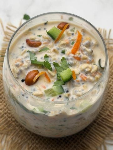 Savory Overnight oats chia in a glass bowl garnished with chopped cucumber, carrot and tempering.