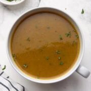 horse gram soup served in a white bowl garnished with cilantro.