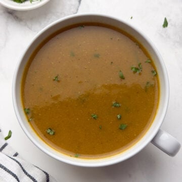 horse gram soup served in a white bowl garnished with cilantro.